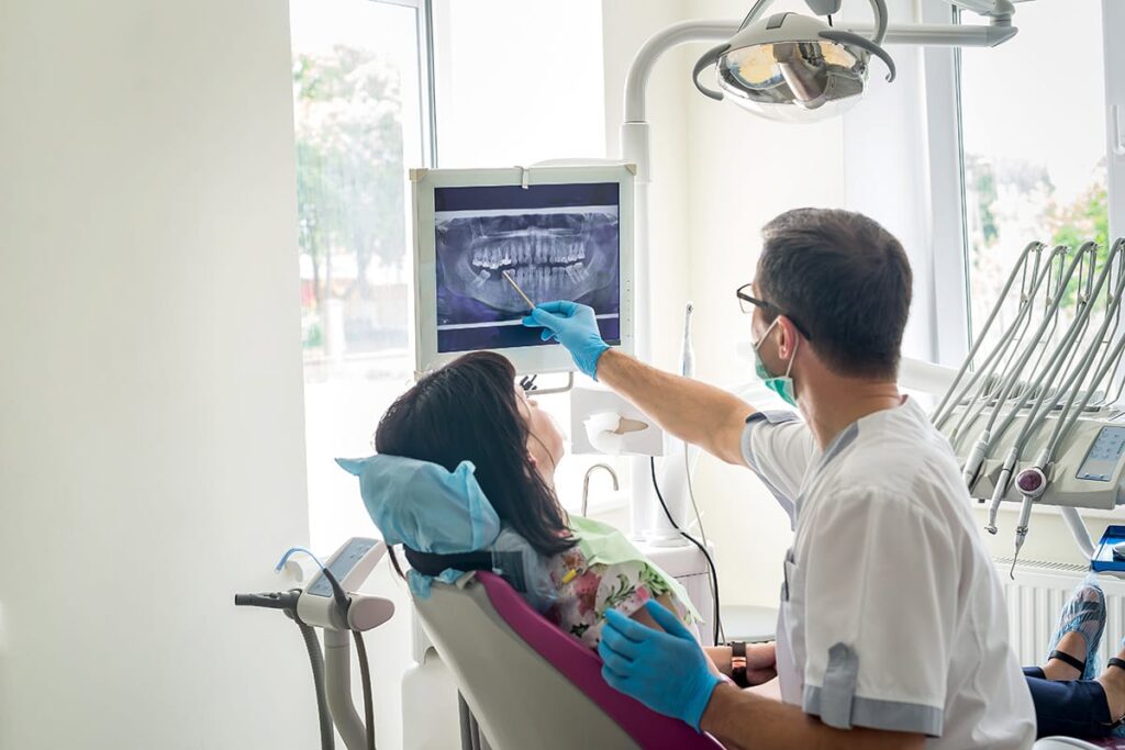 patient and dental care provider discussing what is a prosthodontist and looking at xrays of mouth