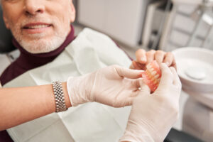 prosthodontist showing patient flexible dentures during office visit